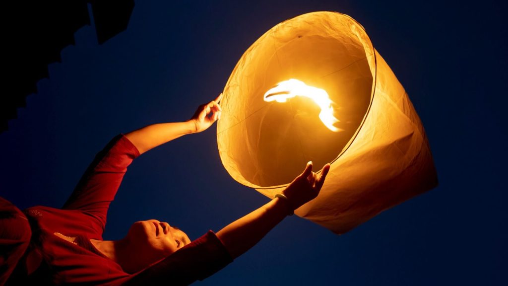 Femme lâchant une lanterne lumineuse dans le ciel de nuit